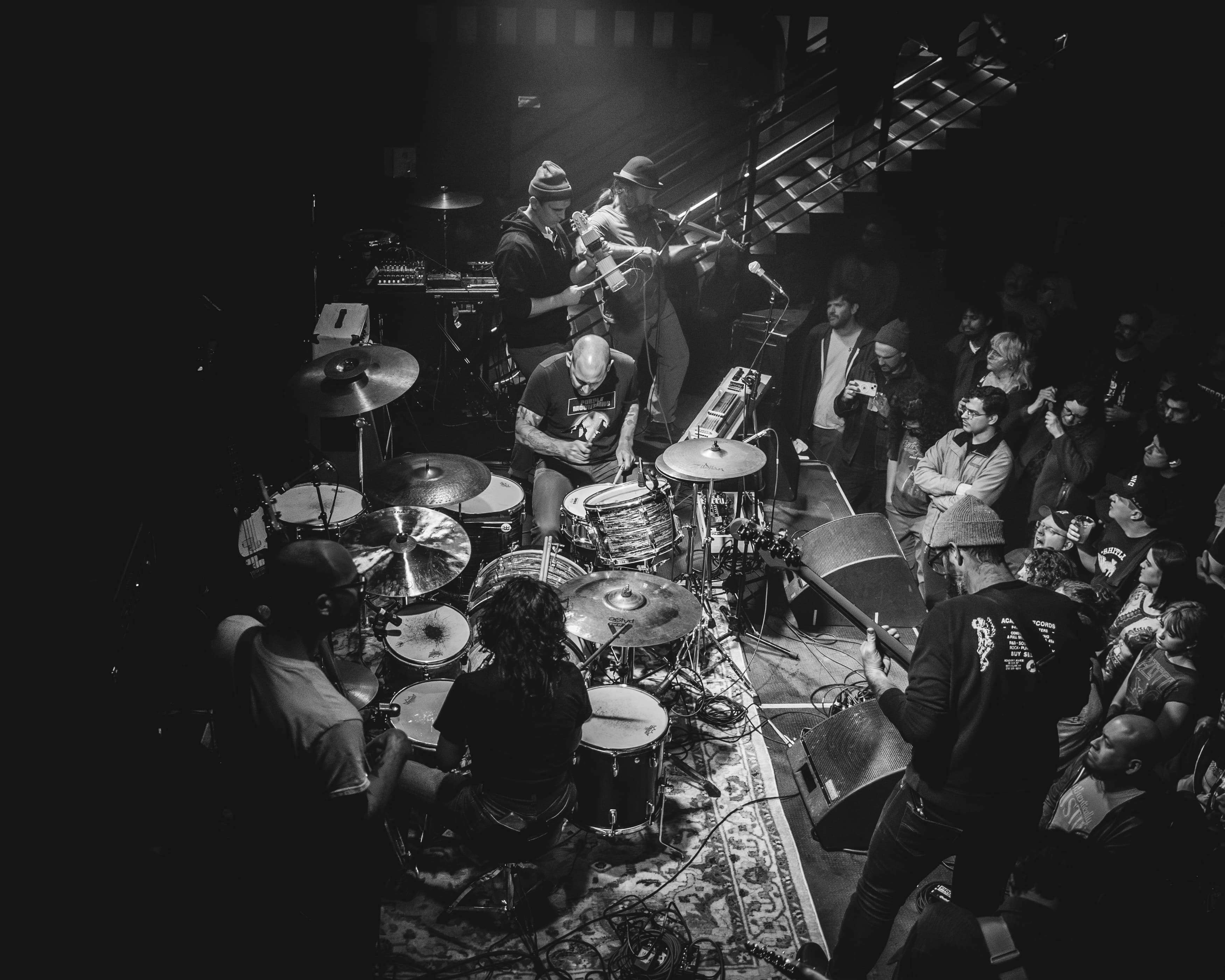 Members of the band Water Damage playing guitars on a dark stage in black and white.