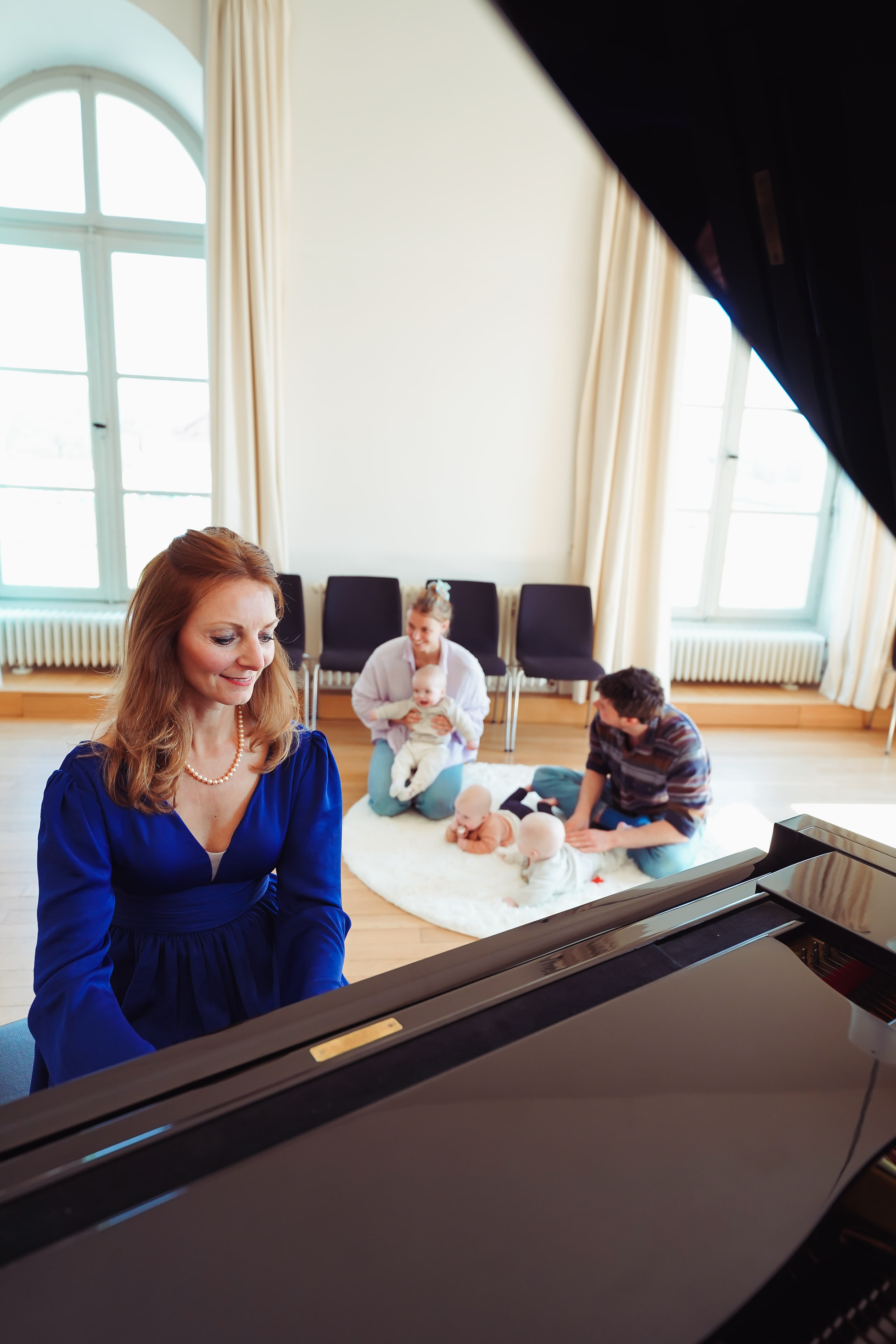 Parents with babies sitting on the floor of a palace hall during a live music session