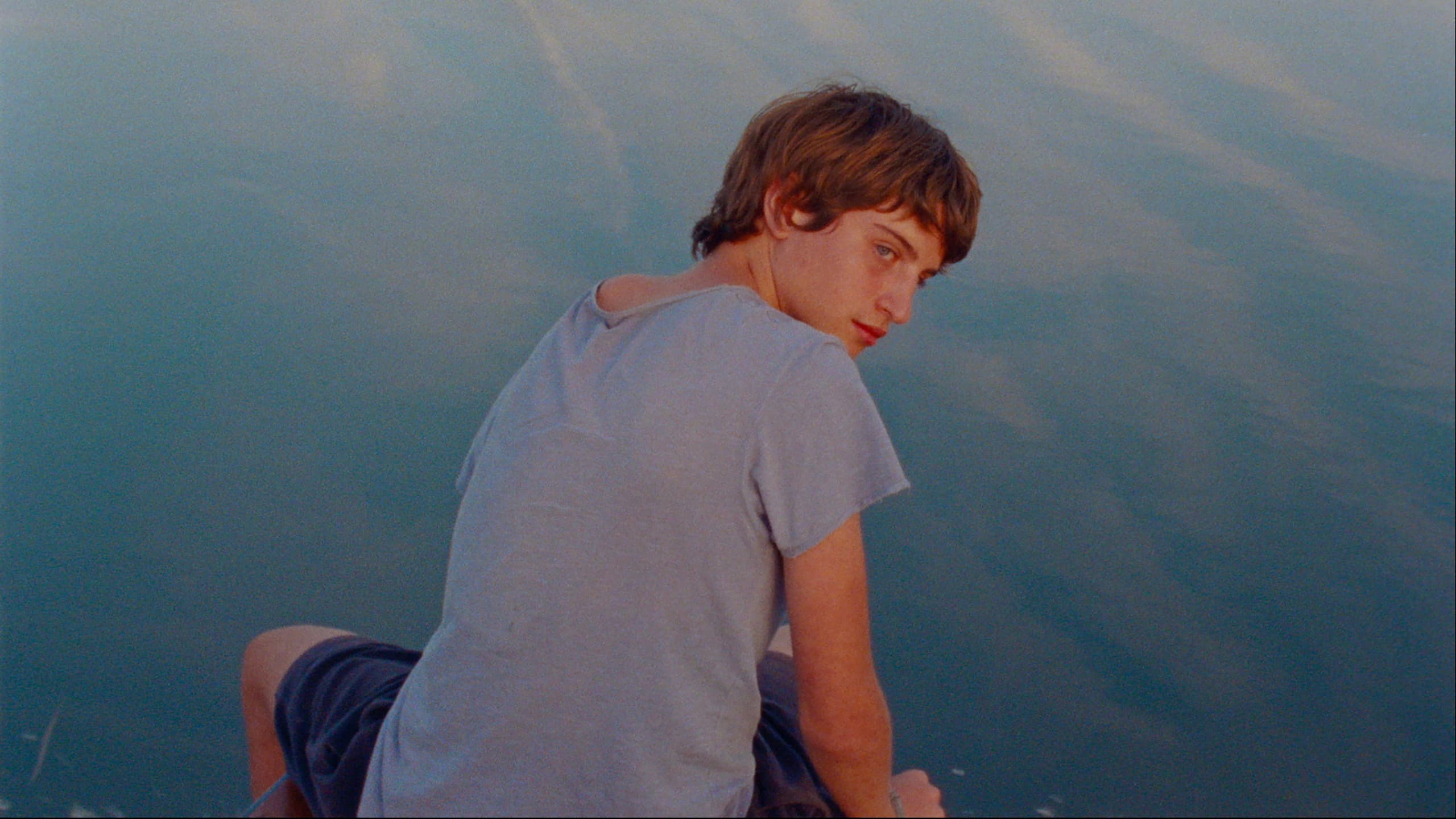 Still from Strange River with a teenager beside a river in summer
