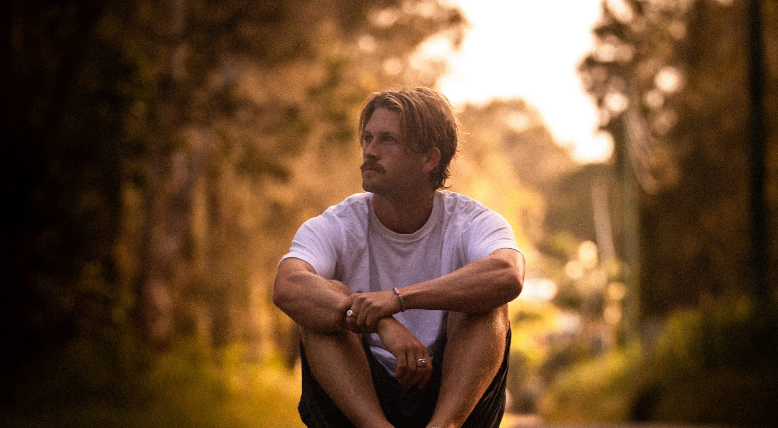 David McCredie photographed outdoors, holding an acoustic guitar.