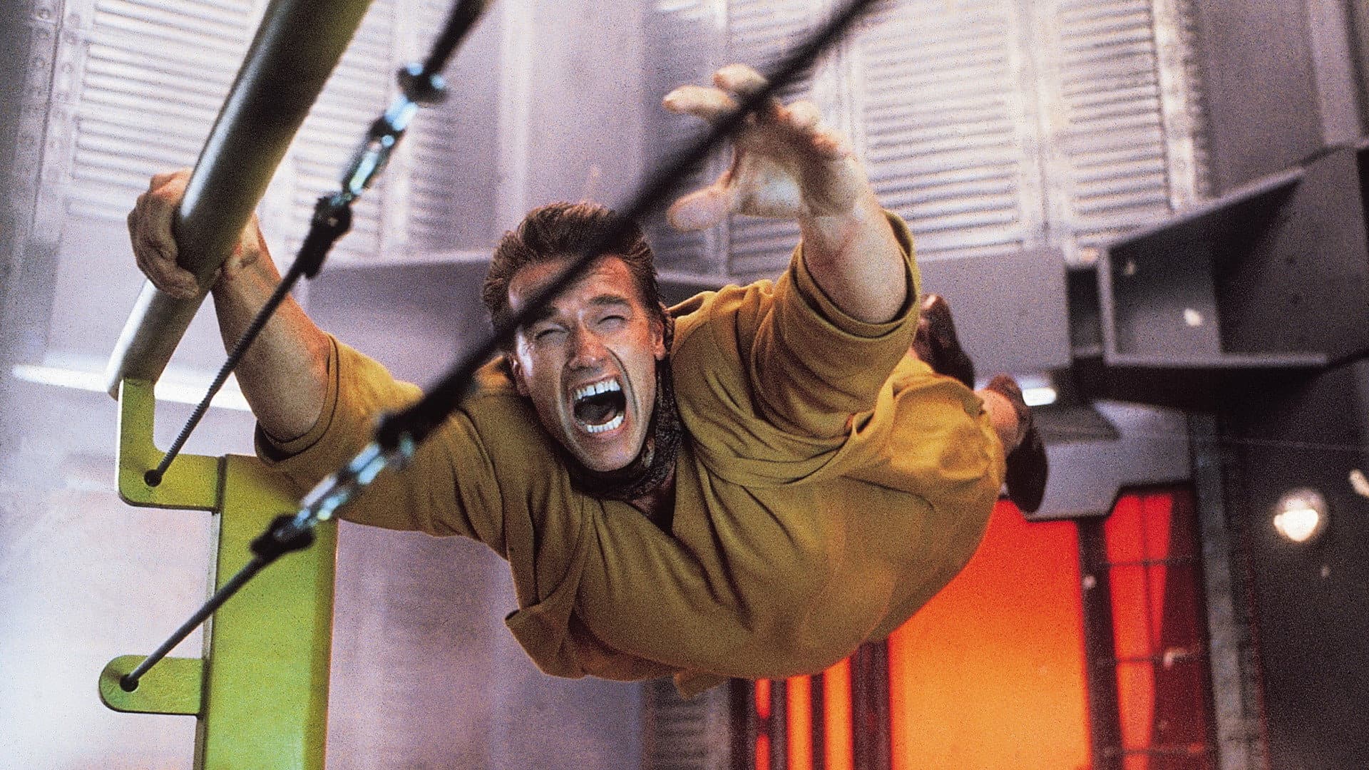 A person screams while hurtling through the air in a futuristic industrial facility, clinging to cables.