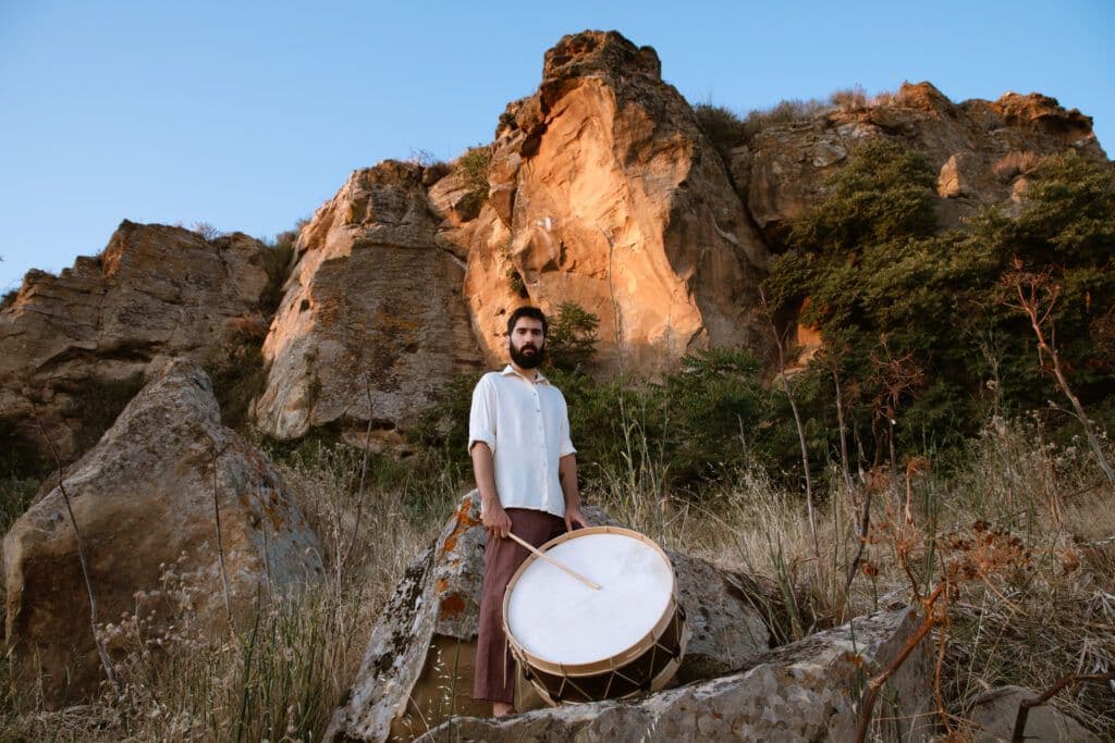 Portrait of musician Davide Ambrogio outdoors, holding a stringed instrument.