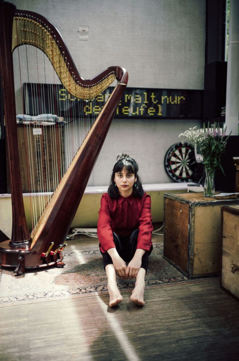Harpist Melis Çom seated at her harp.