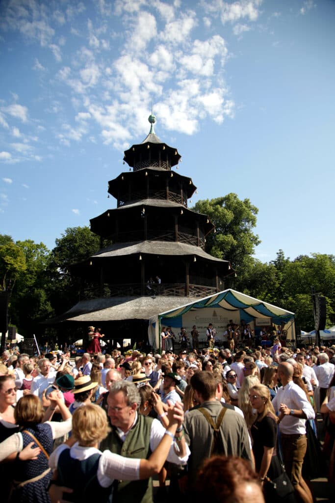 Dancers waltzing in front of the Chinesischer Turm pagoda in the early morning, with a covered bandstand at the Kocherlball.