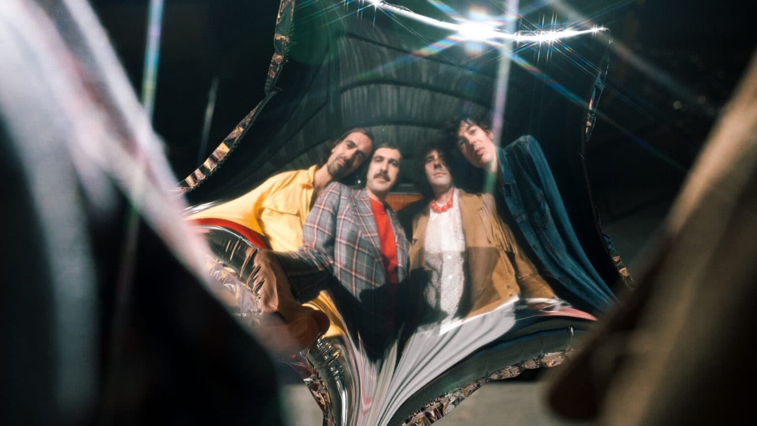 The band Hearts Hearts photographed together in a dim, moody setting.