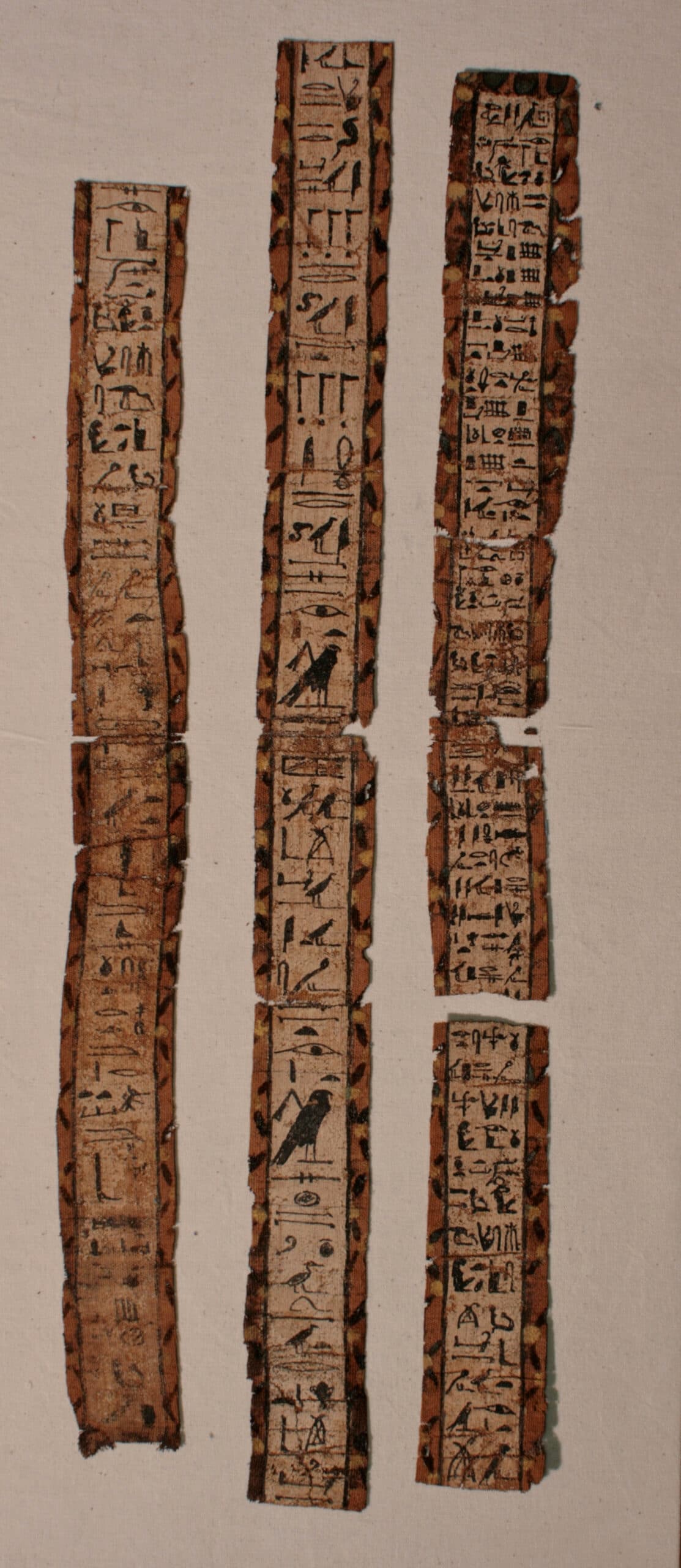 Three long strips of ancient Egyptian inscription.