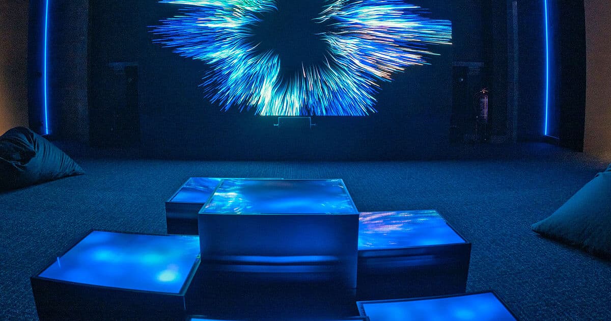 A woman looks towards a glowing blue-green holographic globe in the Future Box.