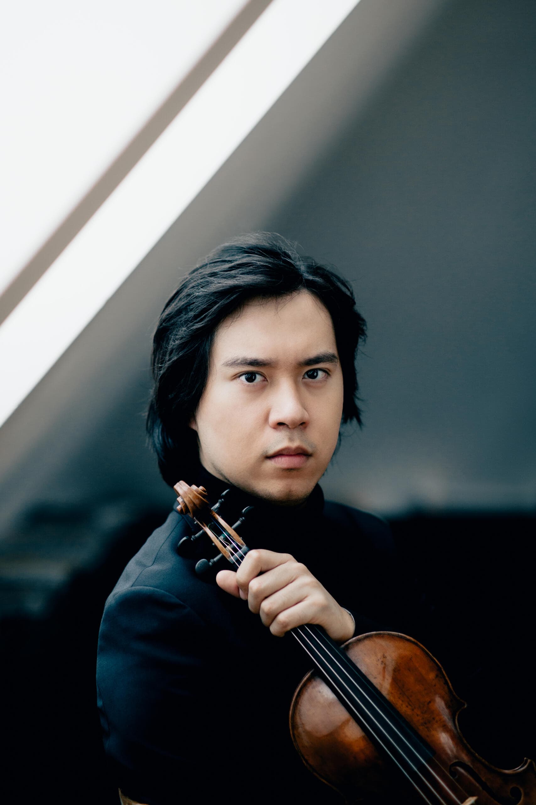 Violinist Elias David Moncado holding his violin for a portrait