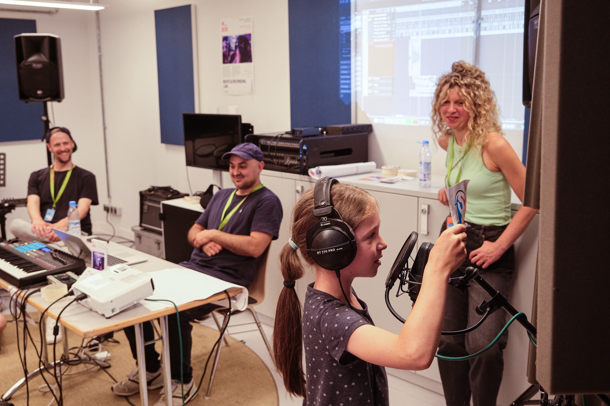 Young people and adults in a recording room with a microphone