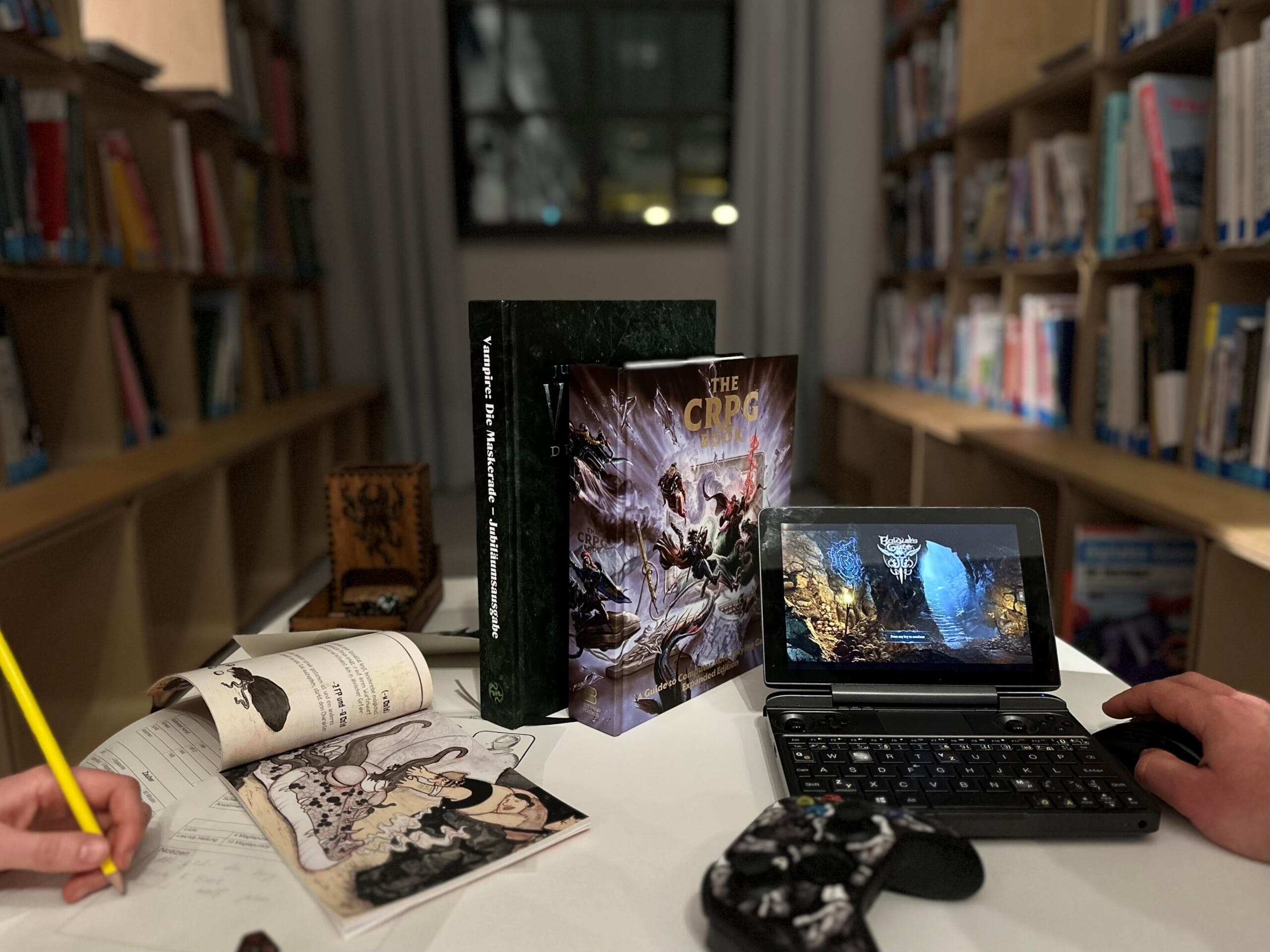 A computer, a joypad and books lie on a table