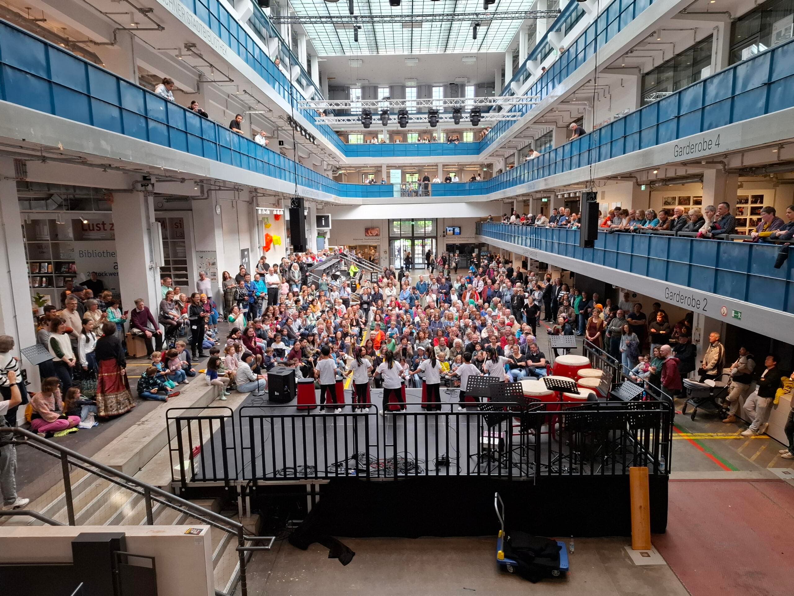 A group drumming on stage in a hall filled with people