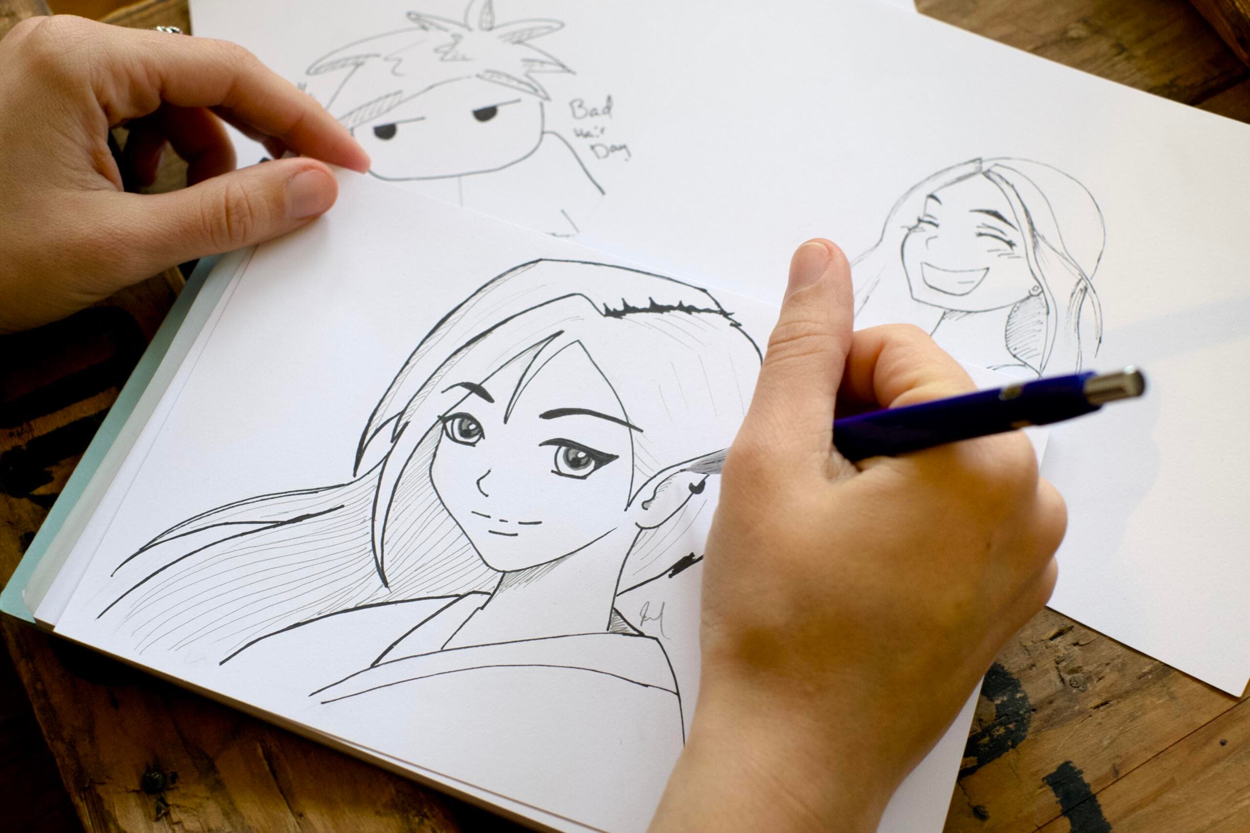 A hand drawing a manga figure on paper