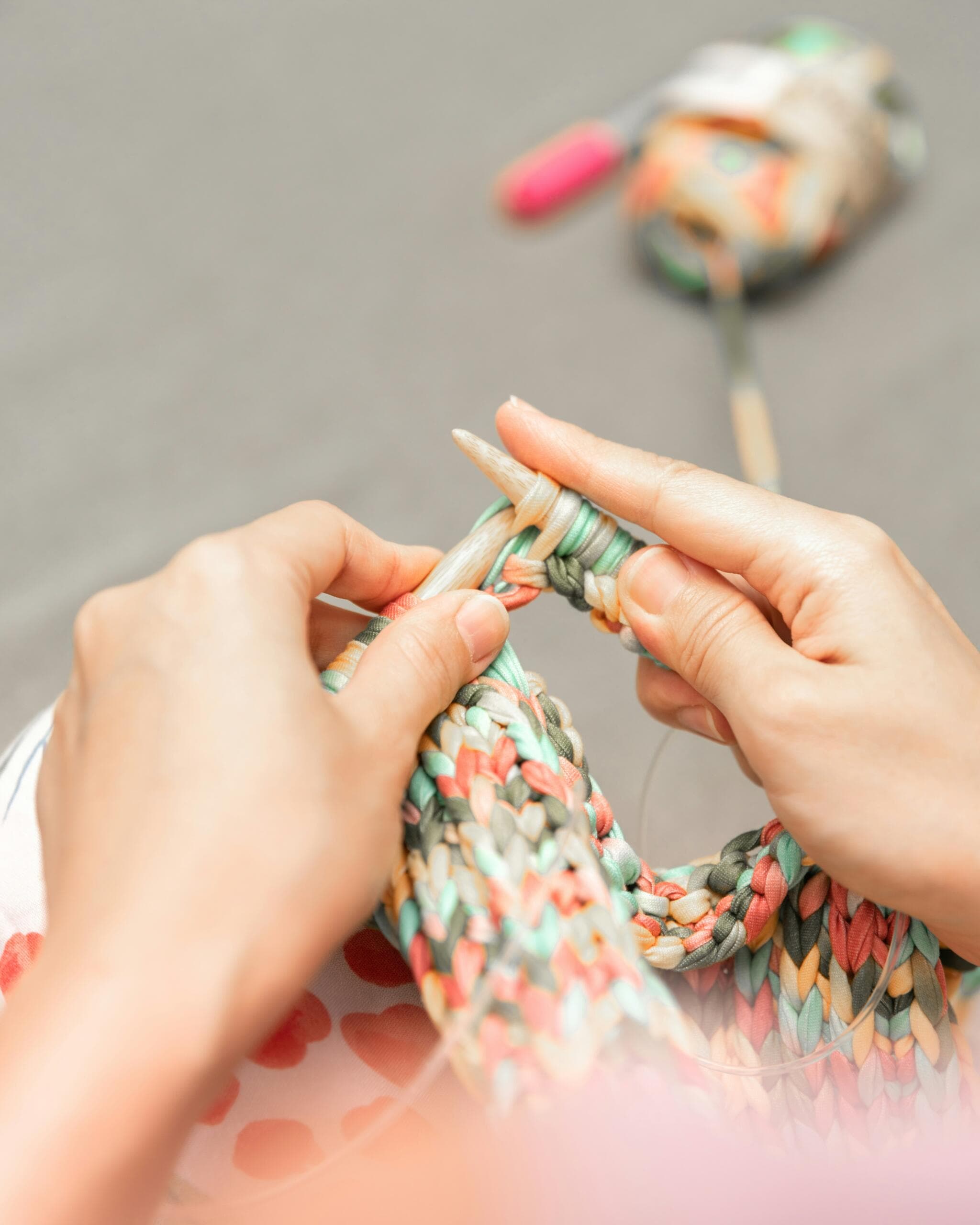 Hands knitting with pale yarn and wooden needles