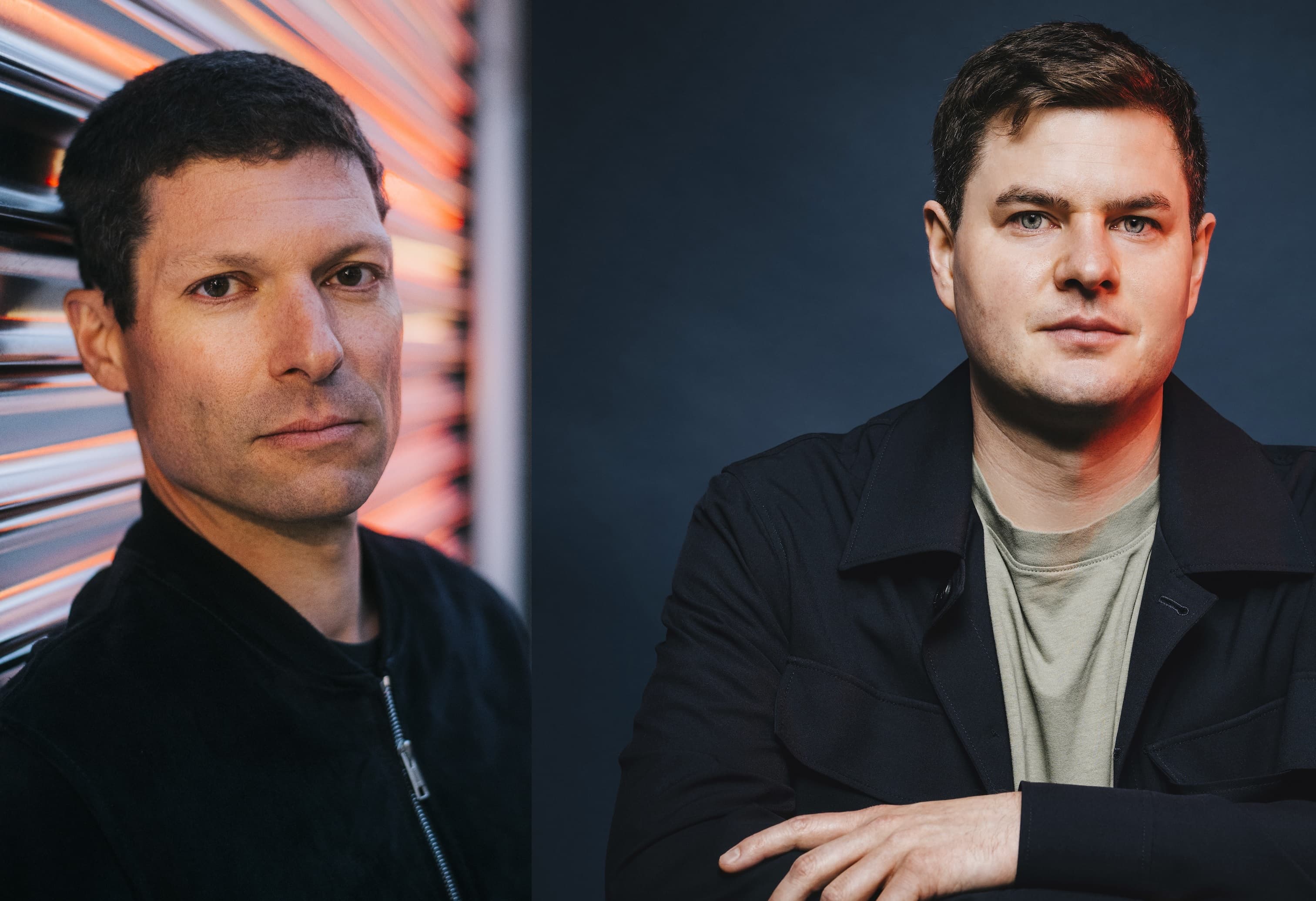Moritz Hürtgen and Ronen Steinke standing side by side against a dark blue wall with window blinds.