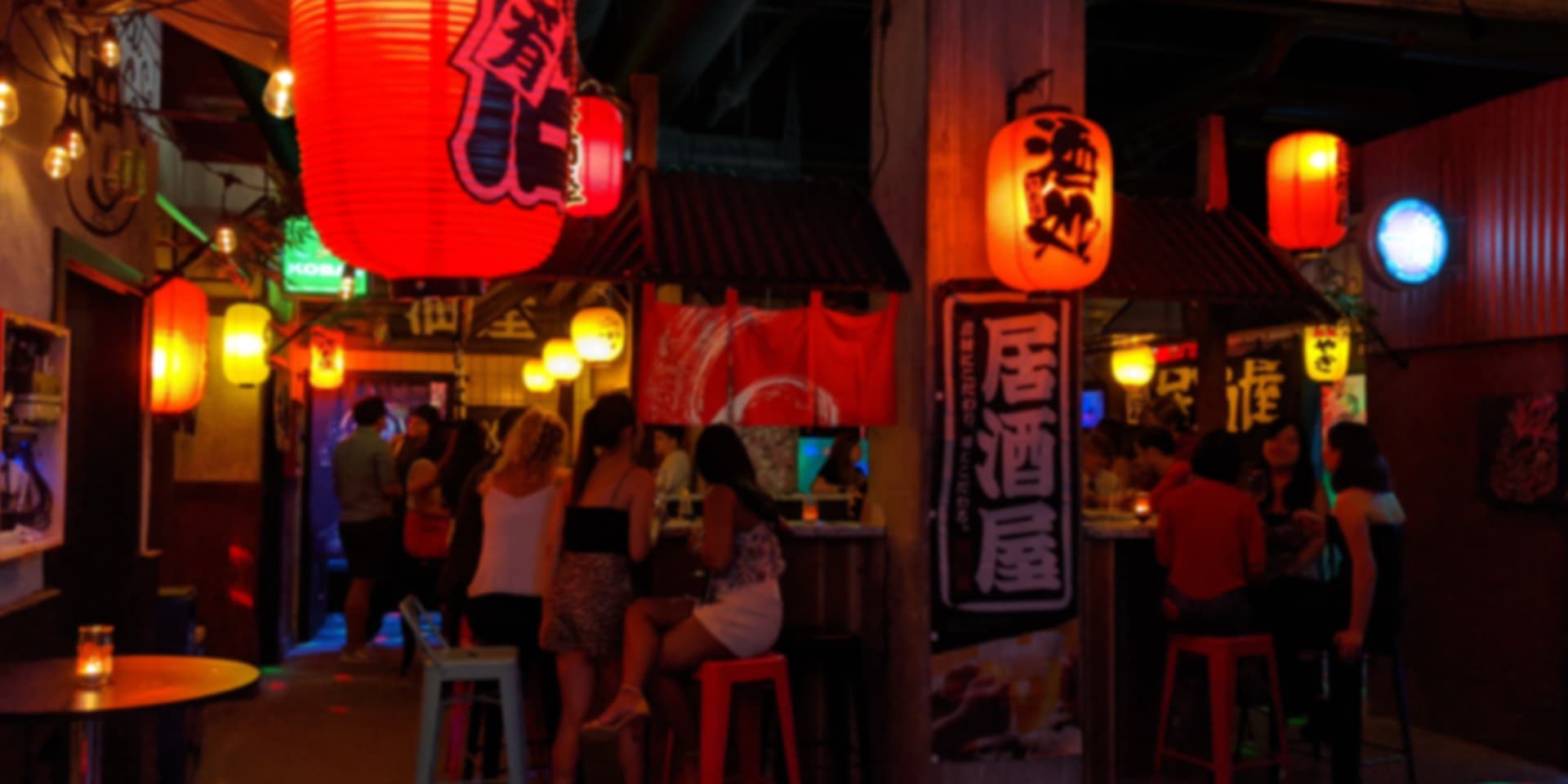 Interior of Yokocho karaoke bar with lantern-lit private singing boxes along a narrow alleyway.